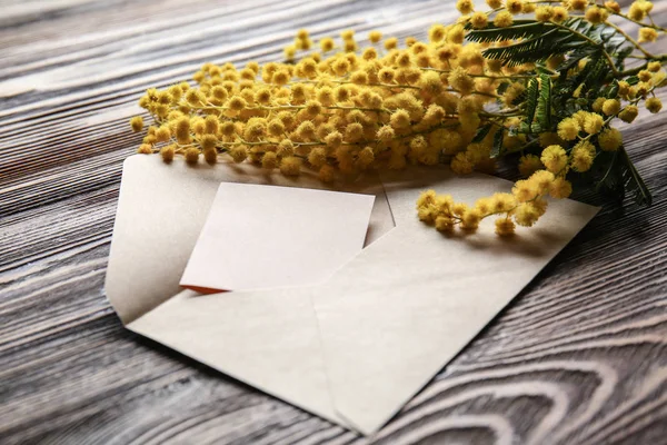 Vackra Mimosa blommor med kuvert på trä bord — Stockfoto