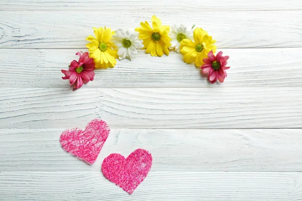 Beyaz ahşap arka planda güzel çiçekler ile pembe kalpler — Stok fotoğraf