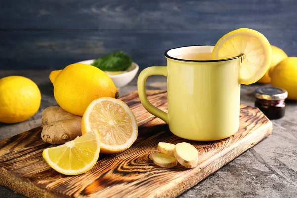 Чашка горячего чая с лимоном и имбирем на деревянной доске — стоковое фото