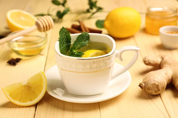 Taza de té caliente con limón y jengibre en la mesa de madera — Foto de Stock