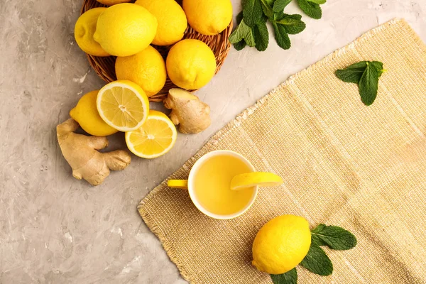 Taza de té caliente con limón, jengibre y menta en la mesa gris —  Fotos de Stock