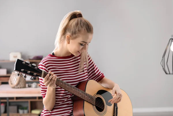 Όμορφη νεαρή γυναίκα παίζει κιθάρα στο σπίτι — Φωτογραφία Αρχείου