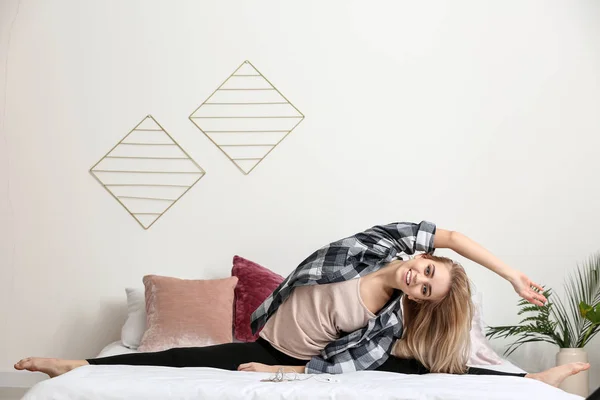 Sporty young woman stretching on bed — Stock Photo, Image