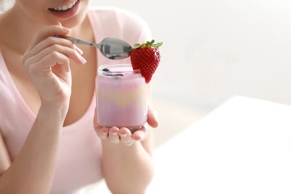 Young woman eating tasty yogurt at home, closeup — Stock Photo, Image