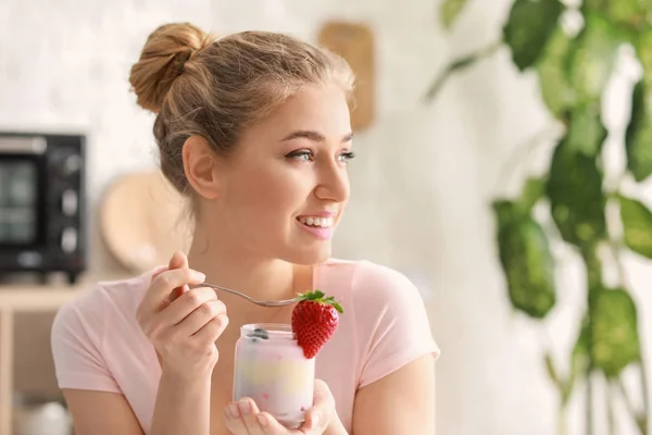 Mladá žena jíst chutný jogurt doma — Stock fotografie