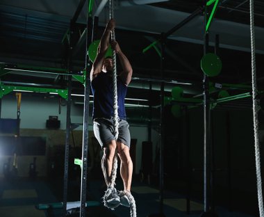 Spor salonunda ip tırmanmaya genç sportif adam