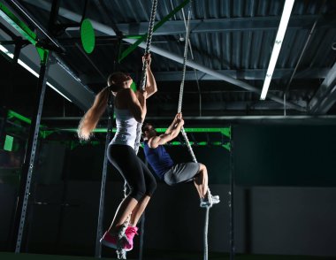 Genç sportif çift spor salonunda ip tırmanıyor