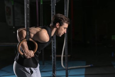 Spor salonunda jimnastik halkaları ile genç sportif adam eğitimi