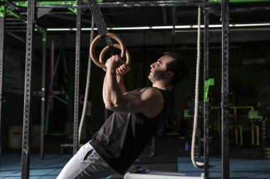 Spor salonunda jimnastik halkaları ile genç sportif adam eğitimi