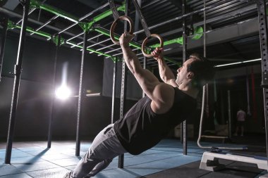 Spor salonunda jimnastik halkaları ile genç sportif adam eğitimi