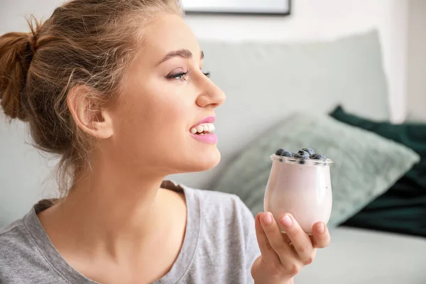 Mujer joven con sabroso yogur en casa — Foto de Stock