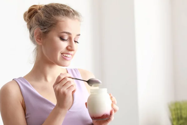 Young woman eating tasty yogurt at home — Stock Photo, Image