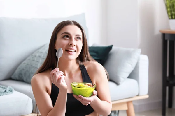 Sporty woman eating tasty yogurt at home — Stock Photo, Image