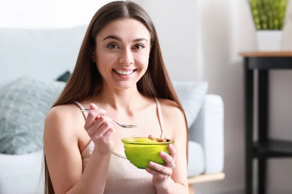 Молодая женщина ест вкусный йогурт дома — стоковое фото