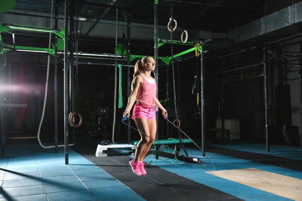 Молодая спортсменка прыгает по веревке в спортзале — стоковое фото