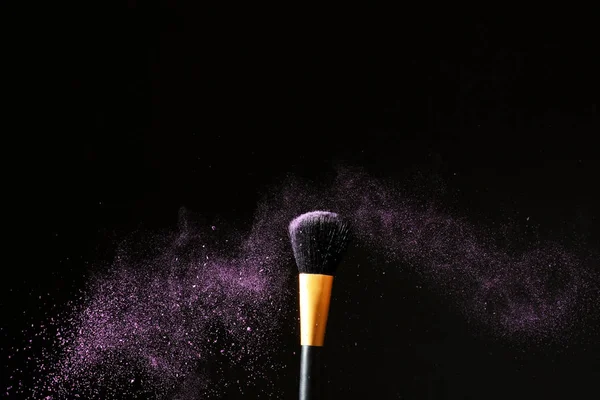 Make-up borstel en uitbarsting van eyeshadows op donkere achtergrond — Stockfoto