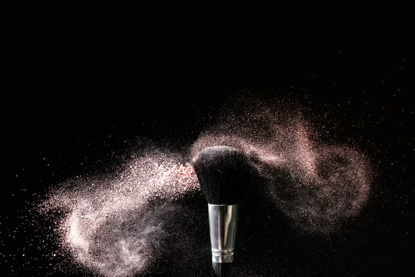 Makeup brush and burst of eyeshadows on dark background — Stock Photo, Image