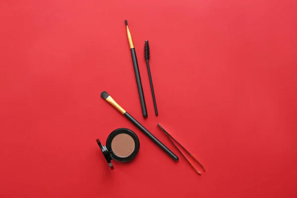 Set of tools for eyebrows correction and eyeshadows on color background