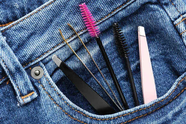 Set of tools for eyebrows correction in jeans pocket, closeup