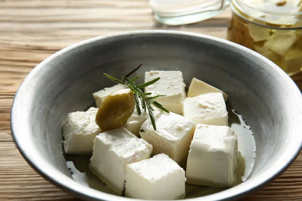Castron cu brânză feta gustoasă în ulei de măsline pe masă de lemn, closeup — Fotografie, imagine de stoc