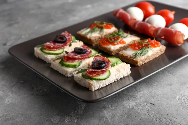 Plate with tasty canapes on grey table — Stock Photo, Image