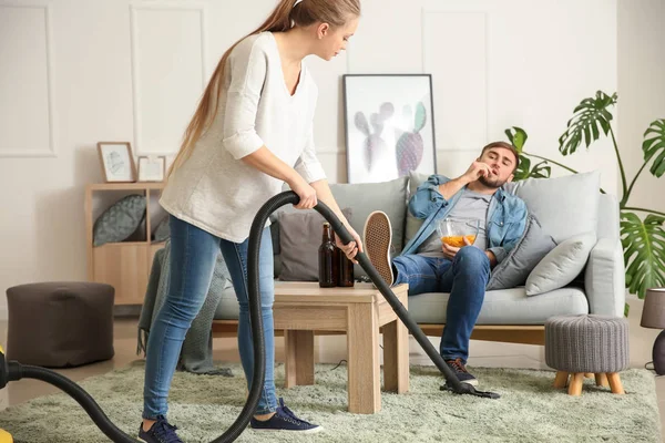 Esposa limpieza piso mientras su marido perezoso viendo la televisión en casa —  Fotos de Stock