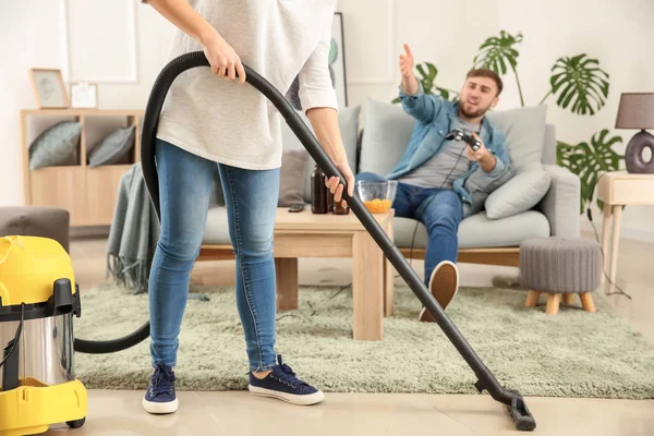 Wife cleaning floor while her lazy husband playing video games at home — Stock Photo, Image