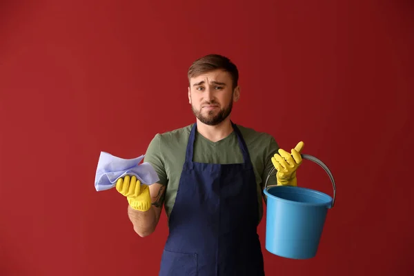 Delusione uomo pigro con prodotti per la pulizia su sfondo di colore — Foto Stock