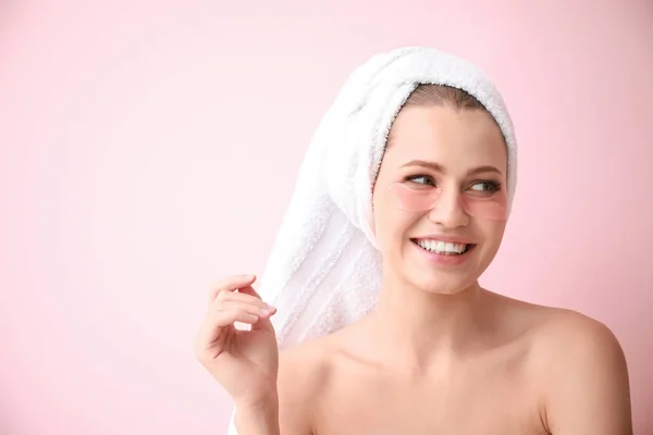 Young woman with under-eye patches on color background — Stock Photo, Image