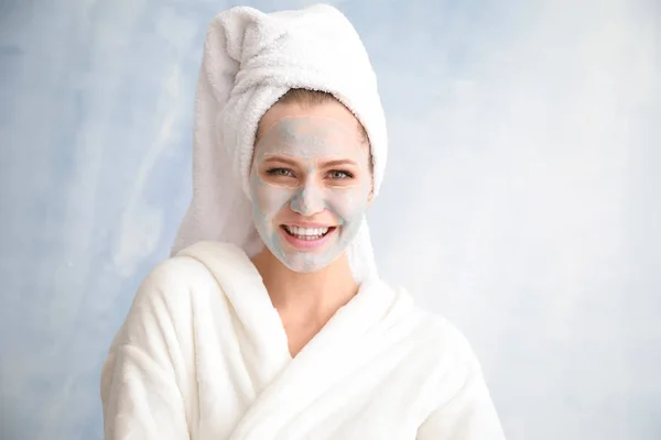 Beautiful young woman with facial mask on light background — Stock Photo, Image
