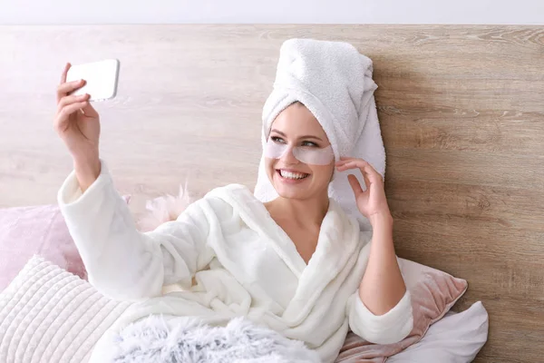 Young woman with under-eye patches taking selfie at home — Stock Photo, Image