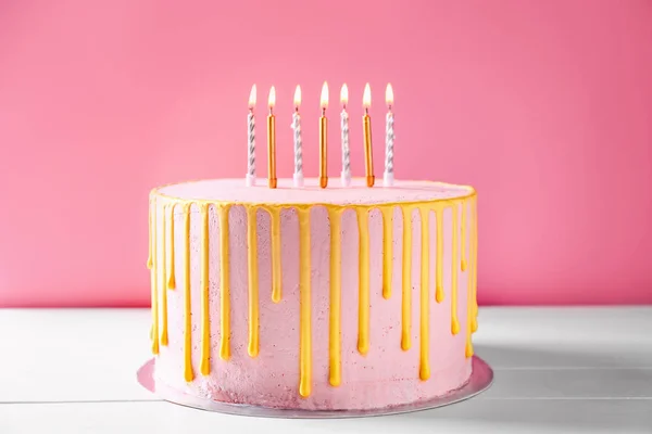 Gâteau savoureux avec des bougies allumées sur une table blanche — Photo