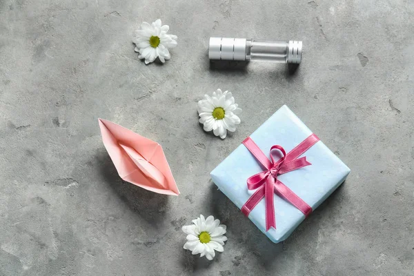 Present ask med flaska parfym, origami båt och blommor på grunge bakgrund — Stockfoto