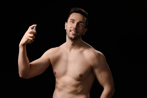 Красивый человек с бутылкой духов на темном фоне
