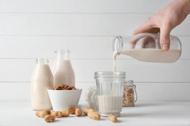 Adam beyaz masada cam içine şişe lezzetli vegan süt dökme
