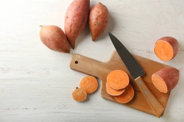 Tahta masa üzerinde ham kesilmiş tatlı patates ve bıçak ile Board