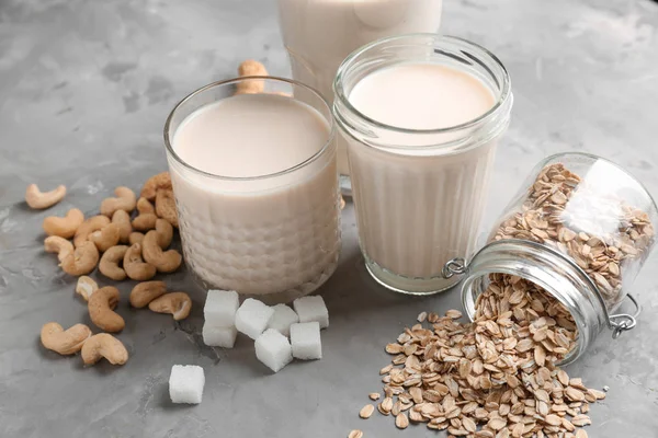 Assortment of tasty vegan milk on grey background — Stock Photo, Image