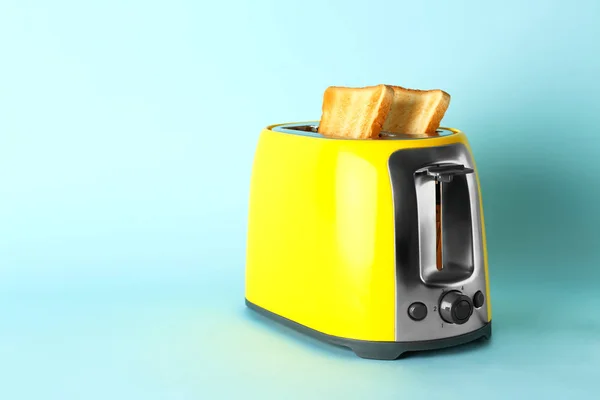 在颜色背景上有面包片的烤面包机 — 图库照片