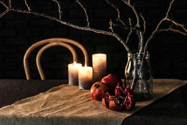 Granátová jablka s větvemi stromu v jar a svíčky na stole před tmavým pozadím — Stock fotografie