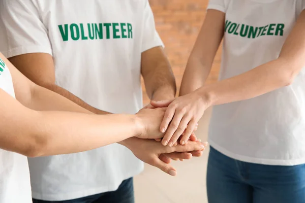 Zespół młodych wolontariuszy wprowadzenie ręce razem pomieszczeniu — Zdjęcie stockowe