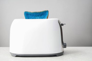 Gri arka plana karşı masada ekmek kızartma makinesi ile boyalı dilim