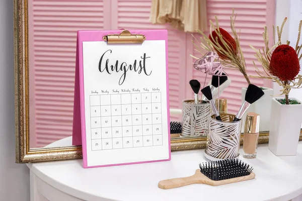 Calendário com acessórios femininos na mesa no quarto — Fotografia de Stock