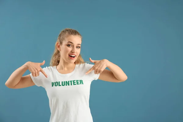 Young female volunteer on color background