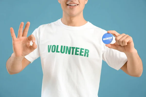 Młody mężczyzna wolontariuszy z odznaka na kolor tła — Zdjęcie stockowe