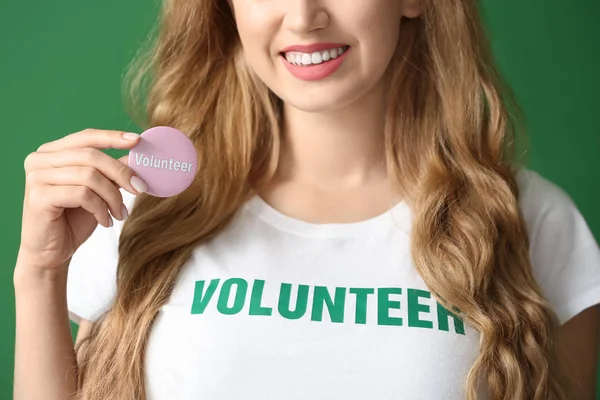Młoda suczka wolontariuszy z odznaka na kolor tła — Zdjęcie stockowe