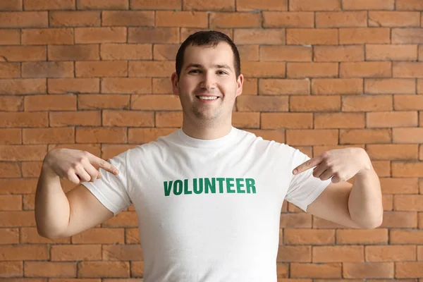 Young male volunteer against brick wall — Stock Photo, Image