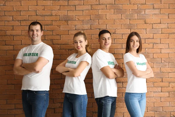 Equipe de jovens voluntários contra a parede de tijolos — Fotografia de Stock