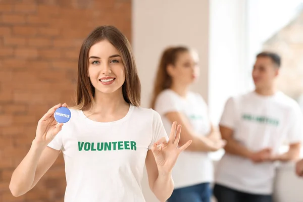 젊은 여성 자원 봉사자와 그녀의 팀 실내 — 스톡 사진