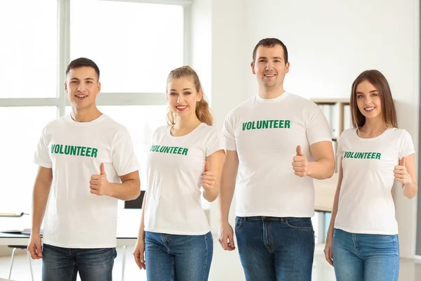 Equipo de jóvenes voluntarios mostrando pulgar hacia arriba en el interior — Foto de Stock