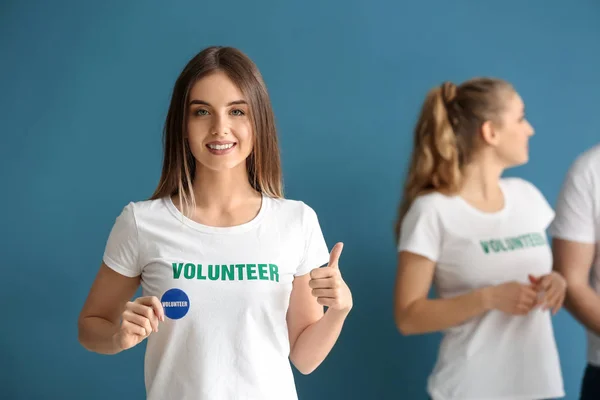 Giovane volontaria femminile e il suo team su sfondo a colori — Foto Stock